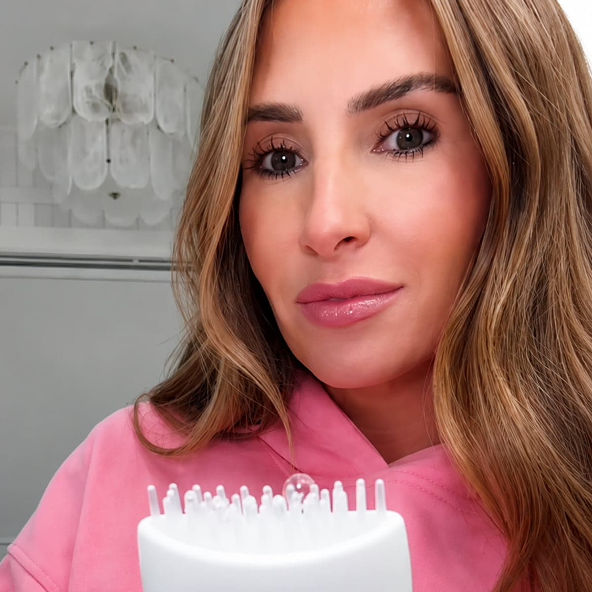 Someone with straight hair holding the serum, brush head facing the camera